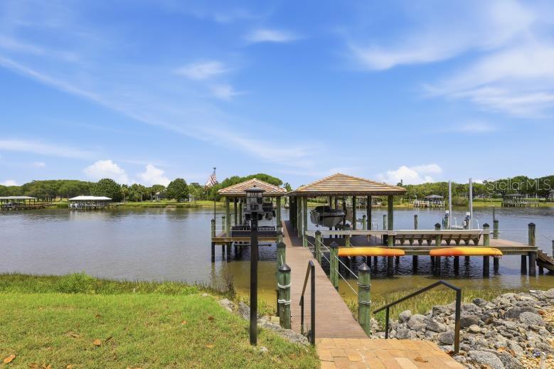 A wooden dock with two covered boat slips extends into a calm river — 34 N WATERVIEW DRIVE, PALM COAST, FL