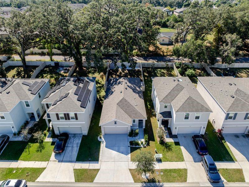 An aerial view shows four suburban houses with driveways and backyards lined by trees — 10945 TRAILING VINE DRIVE, TAMPA, FL