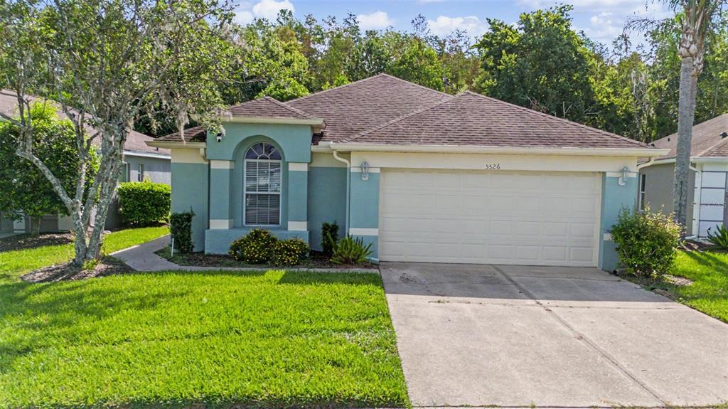 A single-story house with a teal facade, a two-car garage, and a brown shingled roof — 5526 GALLANT FOX COURT, WESLEY CHAPEL, FL
