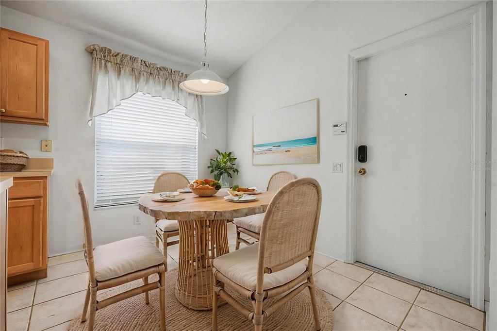 A dining area features a round wooden table, four wicker chairs, and a white door — 5526 GALLANT FOX COURT, WESLEY CHAPEL, FL