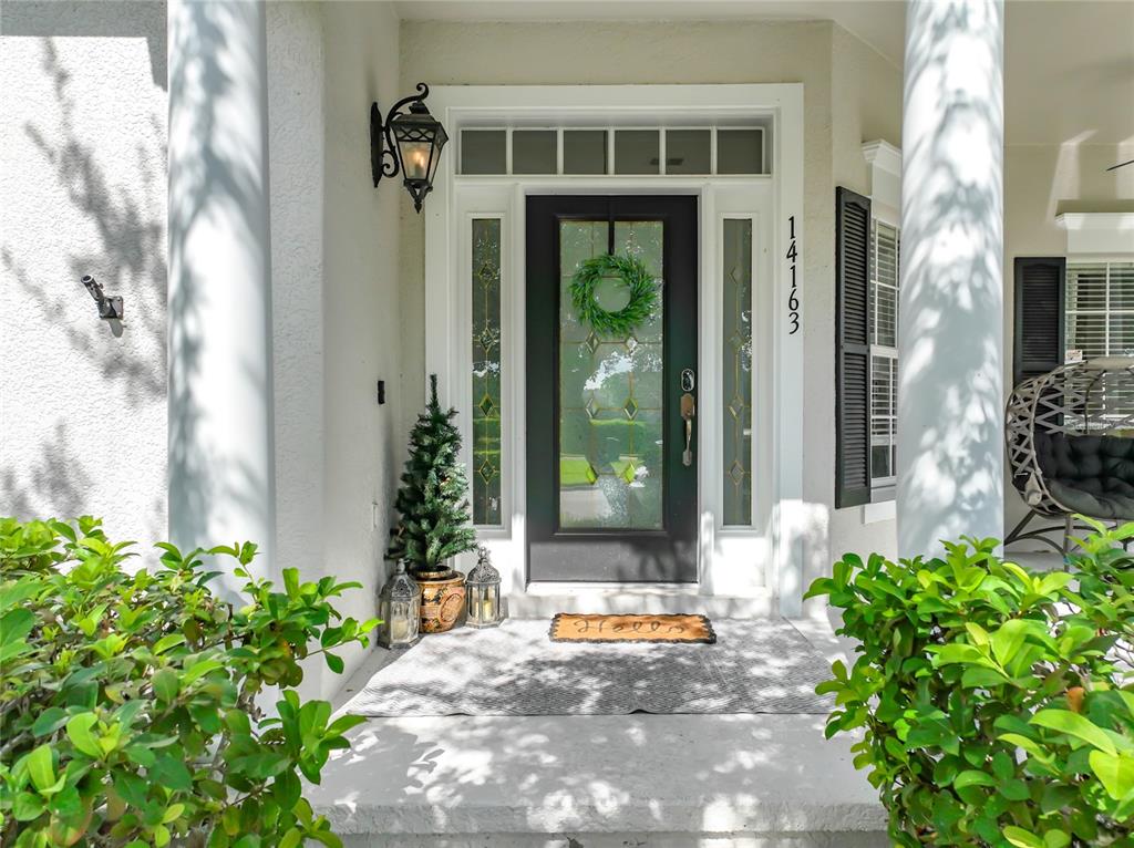 A front entryway features a black door with glass panels, sidelights, and a small Christmas tree — 14163 CHICORA CROSSING BOULEVARD, ORLANDO, FL