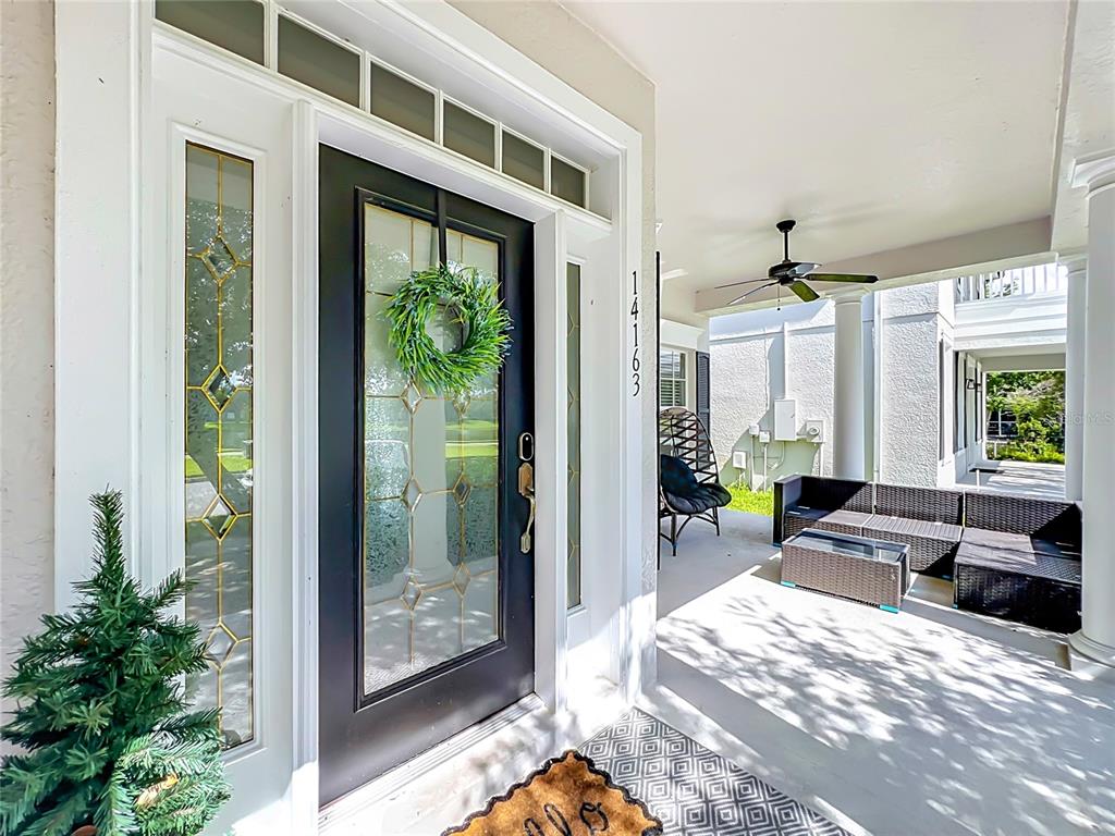 A front porch features a black door with a wreath and outdoor wicker furniture — 14163 CHICORA CROSSING BOULEVARD, ORLANDO, FL