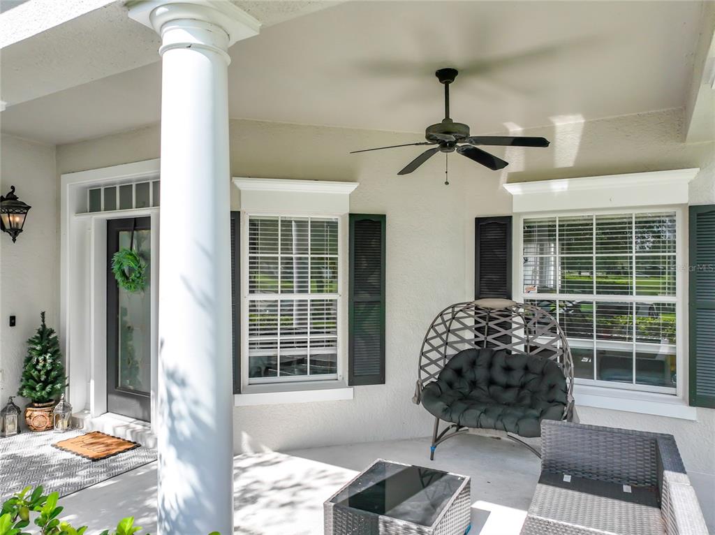 A covered porch features a white column, ceiling fan, windows with shutters, and patio furniture — 14163 CHICORA CROSSING BOULEVARD, ORLANDO, FL