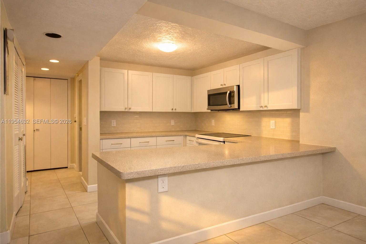 A kitchen features white cabinets, a light-colored countertop, and a tiled backsplash — 104 SW 9th St # 1101, Miami FL 33130, MIAMI, FL
