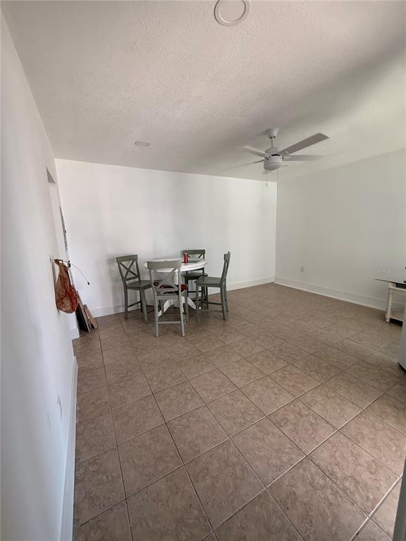 A dining area features tile flooring, a white round table with four chairs, and a ceiling fan — 159 MEDALLION BOULEVARD UNIT A, MADEIRA BEACH, FL