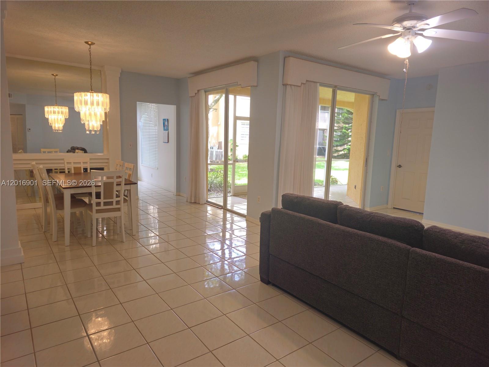 A living and dining area features tile flooring, a ceiling fan, and sliding glass doors — 14715 Balgowan Rd # 9, Miami Lakes FL 33016, MIAMI LAKES, FL