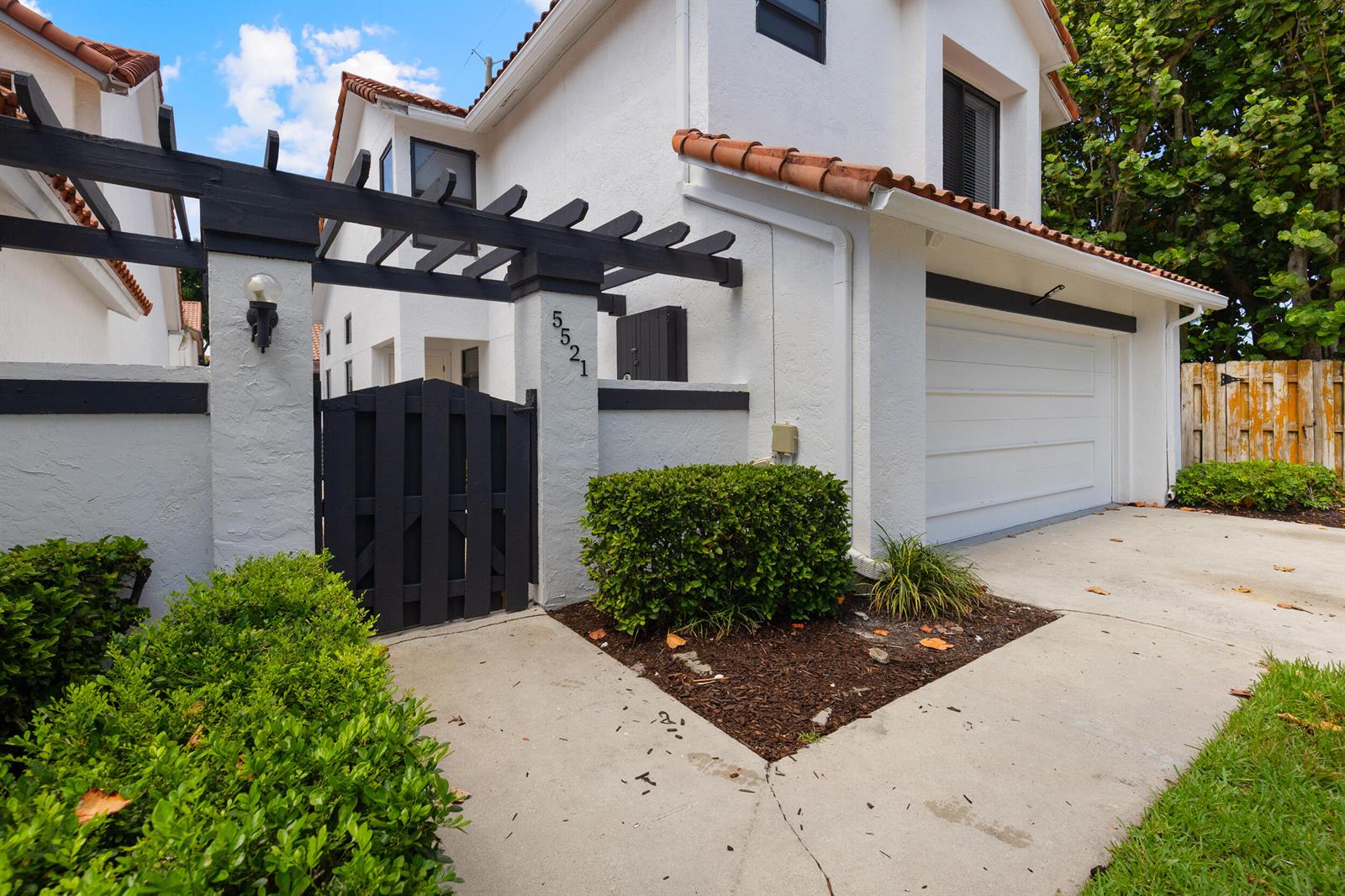 A white two-story house features a black wooden gate, a pergola, and a garage — 5521 Ilford Court, Boca Raton FL 33486, BOCA RATON, FL