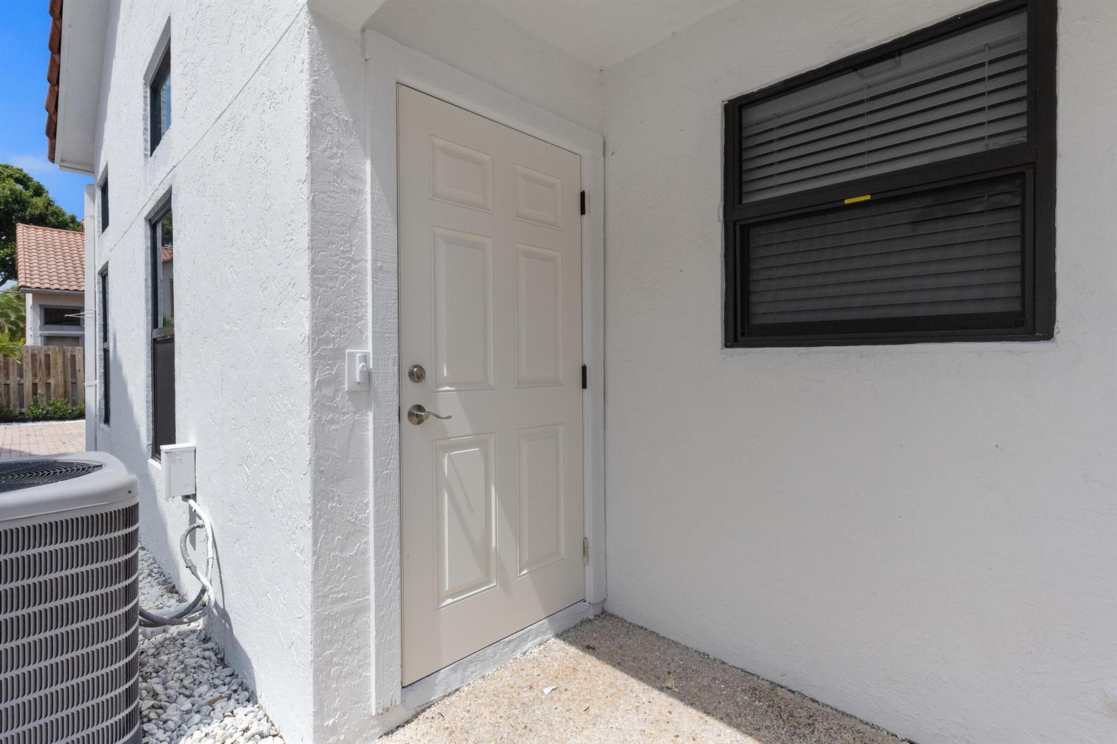 A white exterior door with a silver handle sits next to a window with black trim — 5521 Ilford Court, Boca Raton FL 33486, BOCA RATON, FL