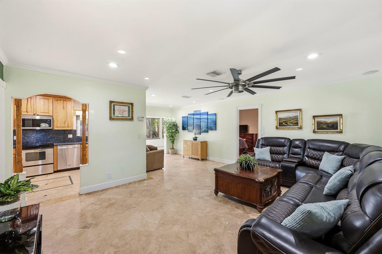 A living room with tile floors, a large leather sectional, and an arched kitchen opening — 390 SE 12th Avenue, Pompano Beach FL 33060, POMPANO BEACH, FL