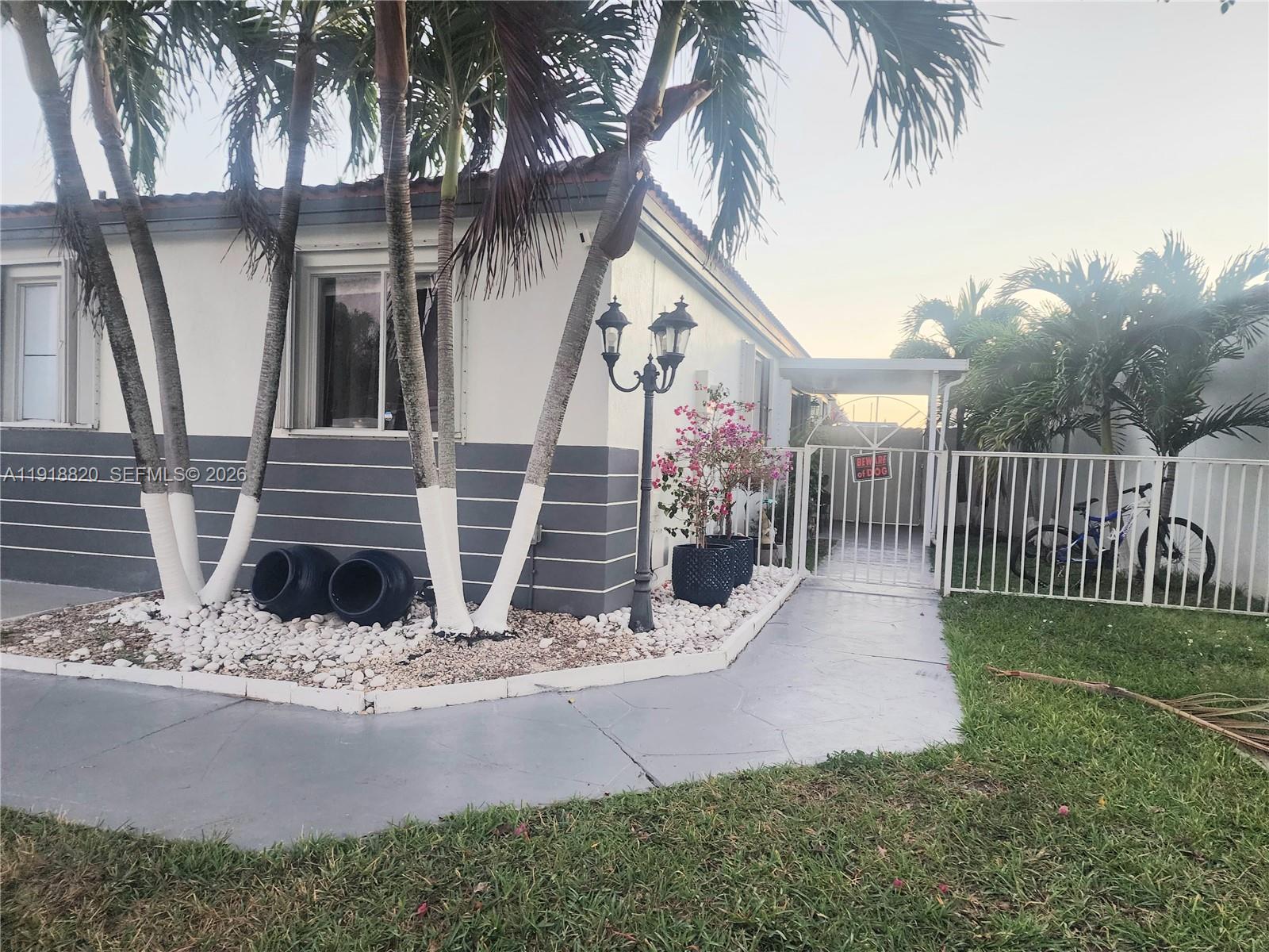 A single-story house exterior features palm trees, a white fence, and a gated walkway — 14291 SW 171st Ter, Miami FL 33177, MIAMI, FL