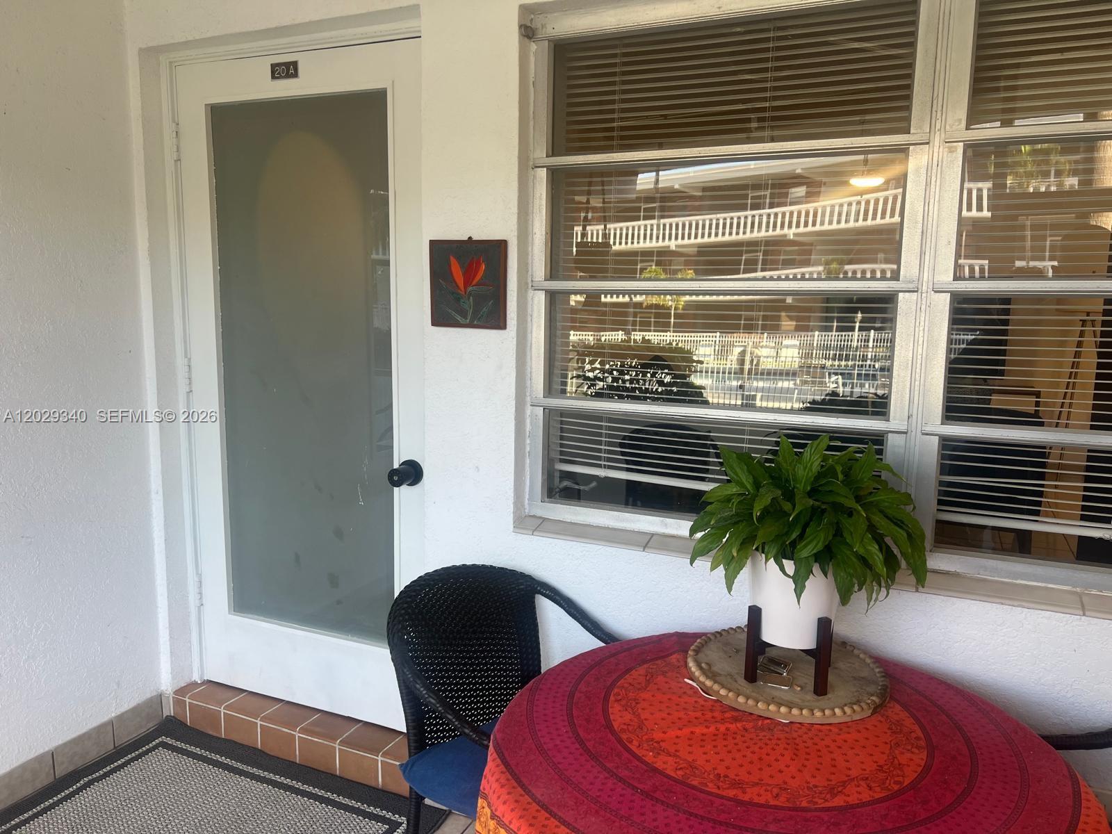 A patio features a small round table with a plant, a chair, and a door — 181 NE 14th Ave # 20A, Hallandale Beach FL 33009, HALLANDALE BEACH, FL