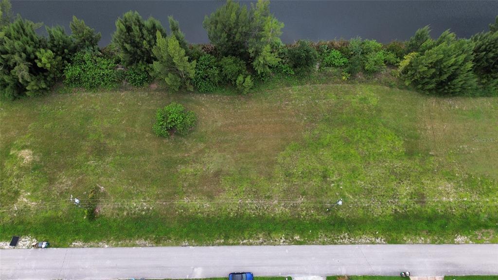 An aerial view shows a vacant grassy lot bordering a body of water — 426 NE 20TH STREET, CAPE CORAL, FL