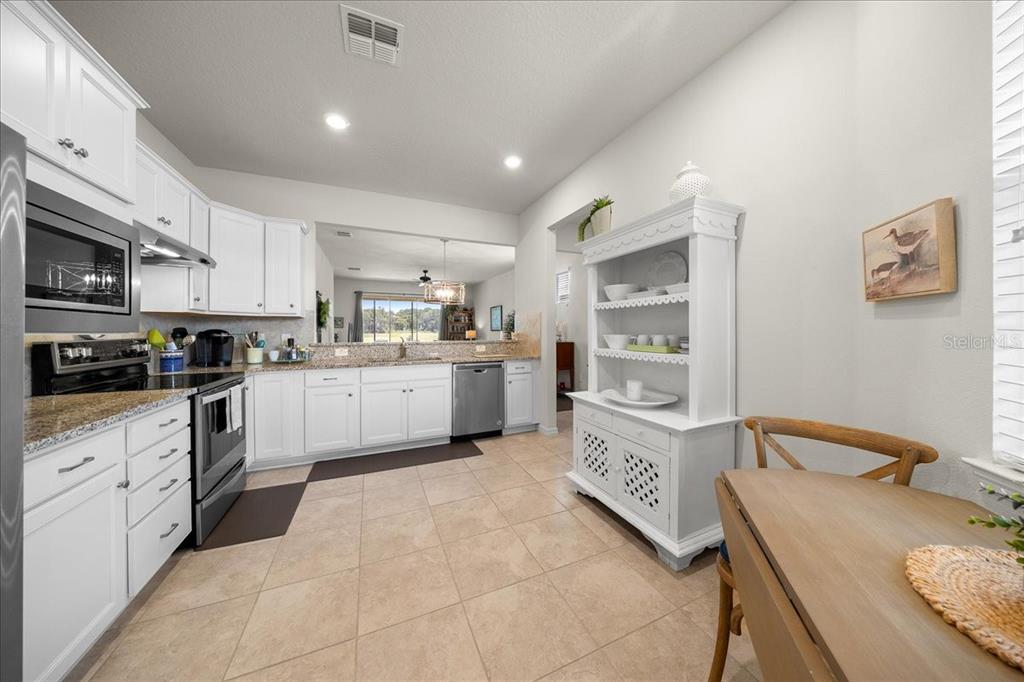 A kitchen features white cabinets, granite countertops, tile flooring, and a white hutch — 9645 SW 63RD LOOP, OCALA, FL