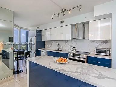 A modern kitchen features blue lower cabinets, white upper cabinets, and a marble-patterned island countertop — 4775 Collins Ave # 2105, Miami Beach FL 33140, MIAMI BEACH, FL