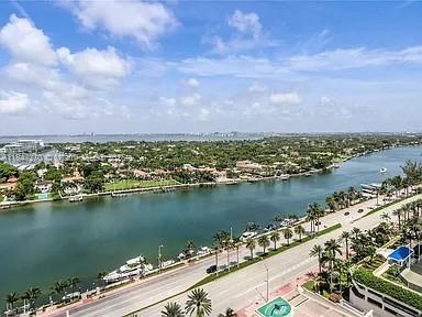 An aerial view shows a waterway lined with boats, palm trees, and a coastal road — 4775 Collins Ave # 2105, Miami Beach FL 33140, MIAMI BEACH, FL