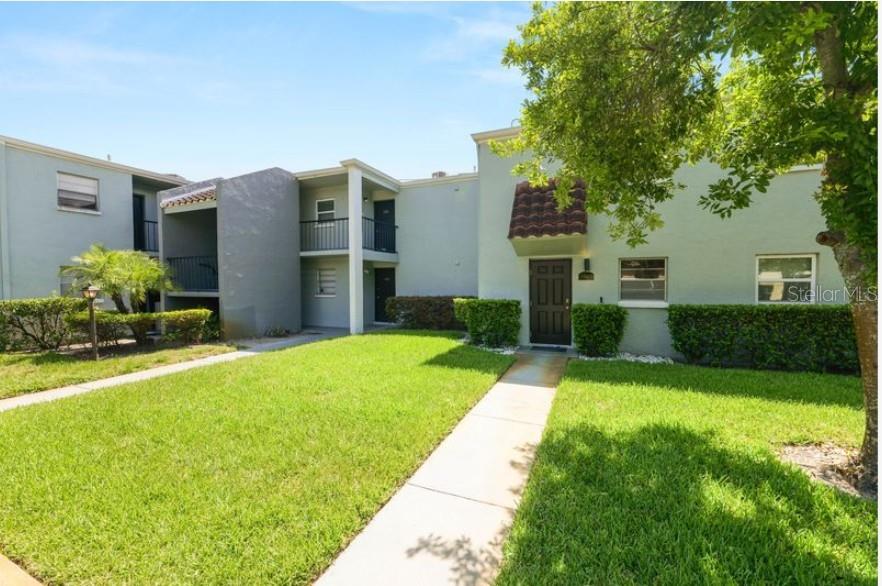 A two-story apartment building exterior features light green stucco walls, a walkway, and landscaping — 2862 SOMERSET PARK DRIVE UNIT 2862, TAMPA, FL