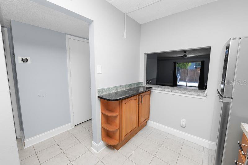 A kitchen area features light gray walls, tile flooring, wooden cabinets, and a pass-through window — 2862 SOMERSET PARK DRIVE UNIT 2862, TAMPA, FL