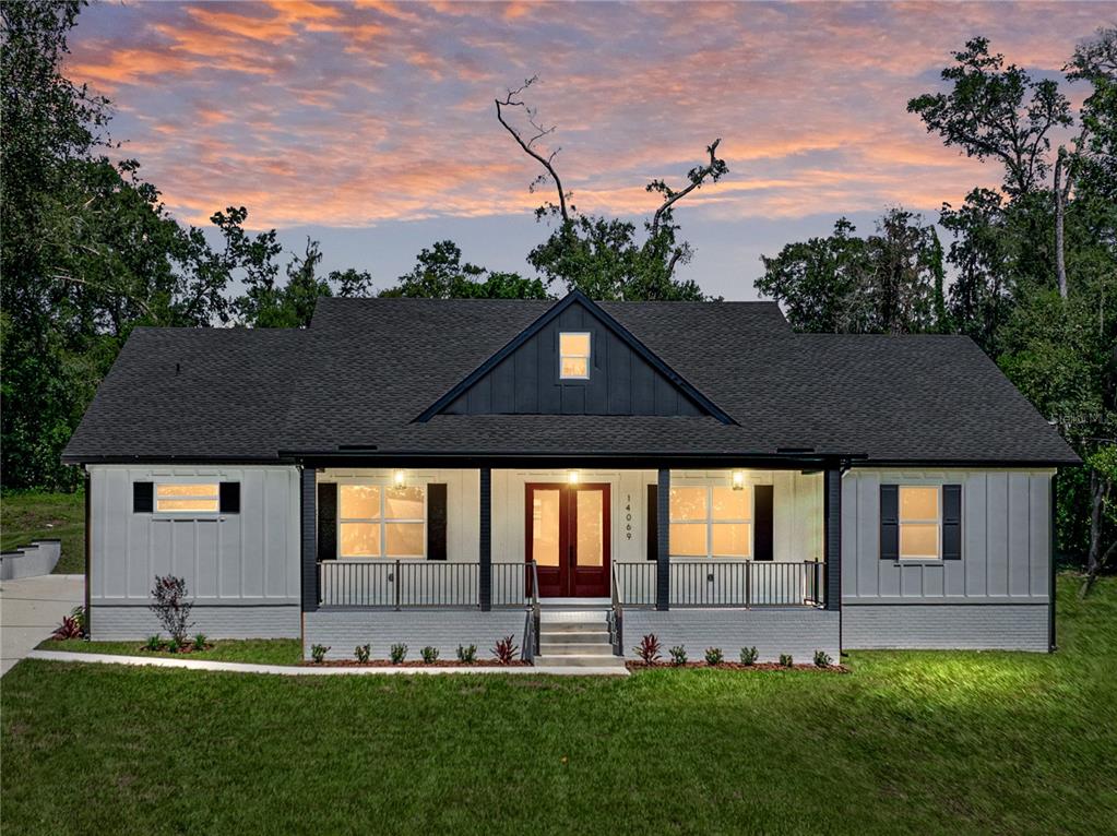 A single-story house with white vertical siding, a dark roof, and a red front door — 14069 GRANDEUR WAY, DADE CITY, FL