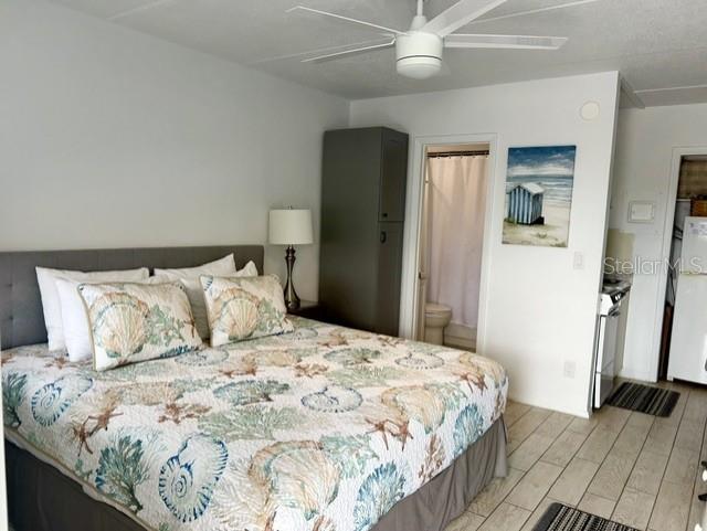 A bedroom features a bed with a seashell-patterned quilt, a ceiling fan, and an attached bathroom — 908 VILLAS DRIVE UNIT 68, VENICE, FL