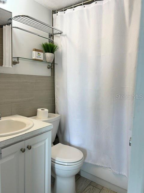 A bathroom features a white vanity, a toilet, and a shower with a white curtain — 908 VILLAS DRIVE UNIT 68, VENICE, FL