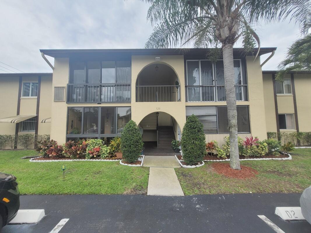 A two-story apartment building exterior with a central arched entryway and screened-in balconies — 320 Pine Ridge Circle # A1, FL 33463, FL