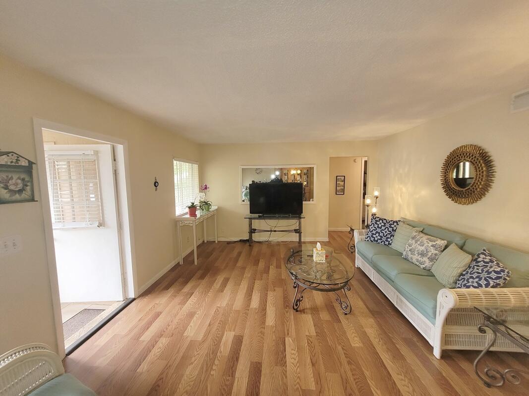 A living room features light wood flooring, a light blue sofa, and a television stand — 320 Pine Ridge Circle # A1, FL 33463, FL