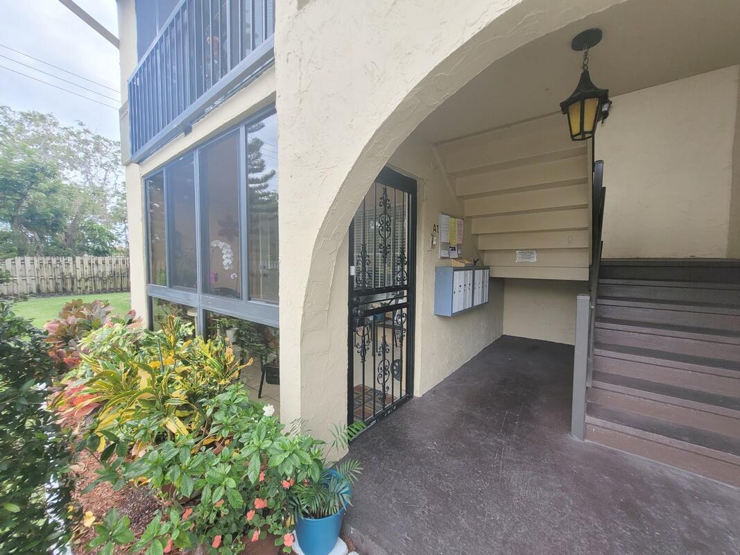 An exterior view of a building entrance with a screened porch, stairs, and mailboxes — 320 Pine Ridge Circle # A1, FL 33463, FL