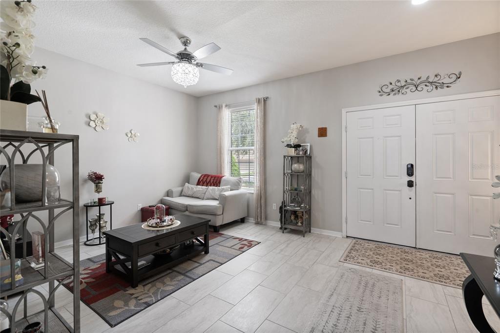 A bright entryway features light tile flooring, a ceiling fan, and a small seating area — 12532 SAWGRASS OAK STREET, ORLANDO, FL