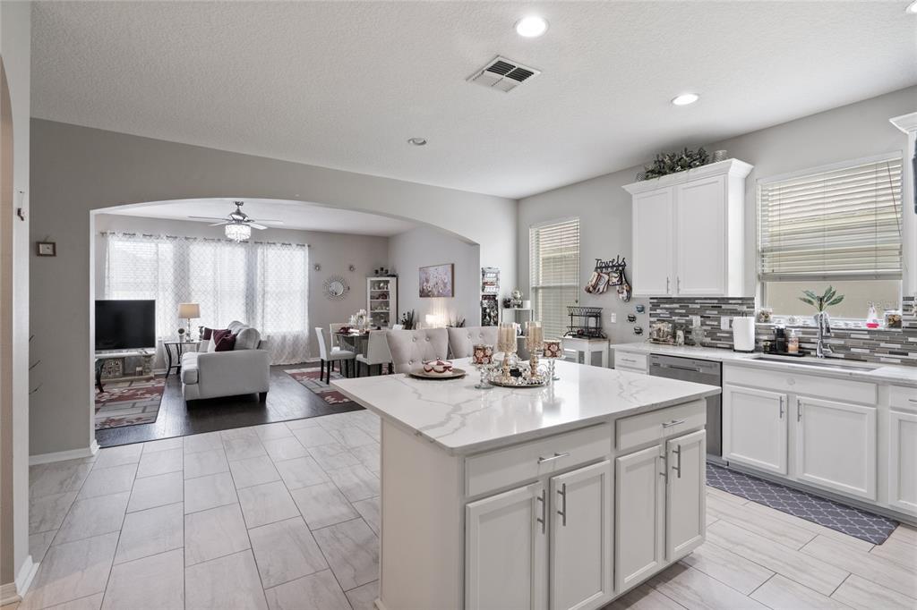 A kitchen with a white marble island and cabinets opens into a living and dining area — 12532 SAWGRASS OAK STREET, ORLANDO, FL