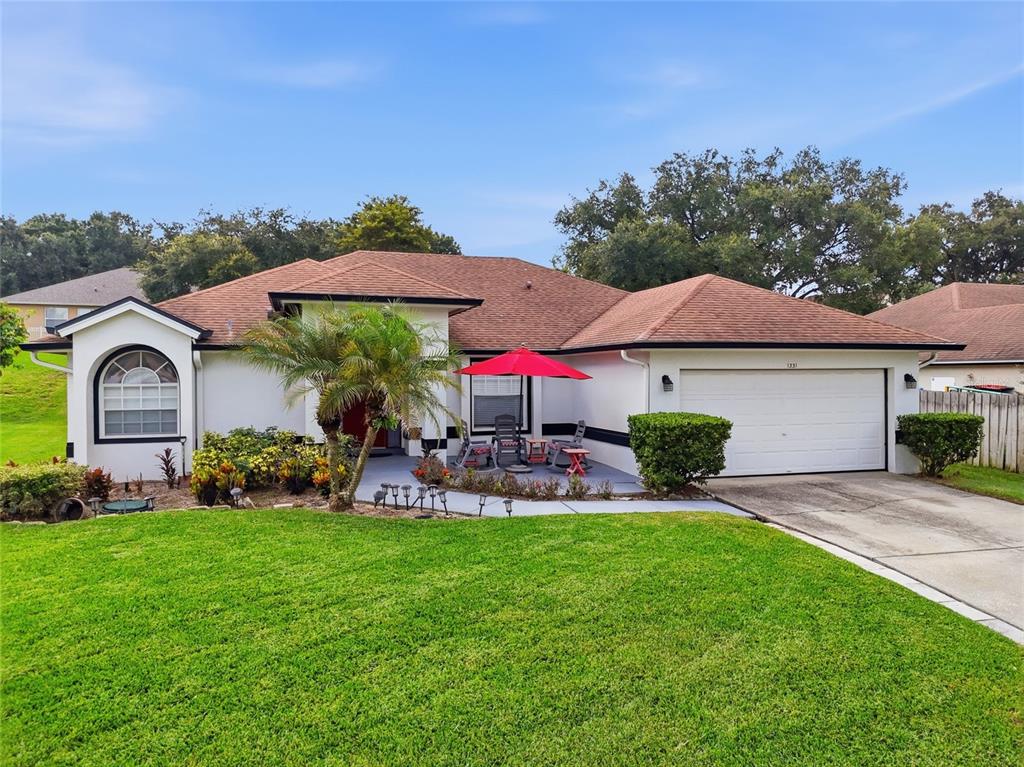 A single-story house with a white exterior, brown roof, and a front patio with furniture — 1331 COUNTRYRIDGE PLACE, ORLANDO, FL