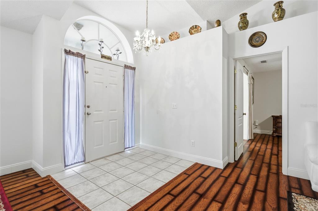 An entryway features a white front door, tile flooring, a chandelier, and wood-look laminate floors — 1331 COUNTRYRIDGE PLACE, ORLANDO, FL