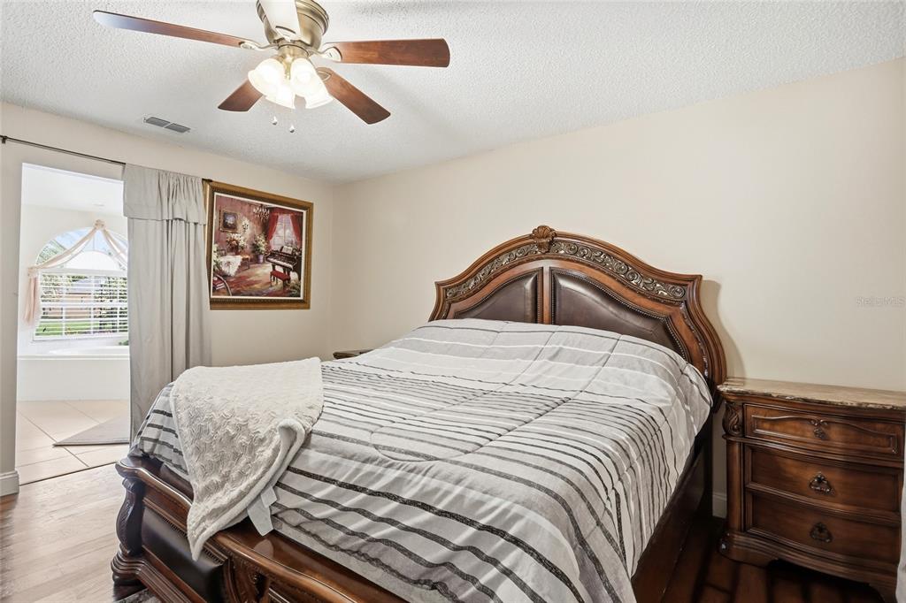 A bedroom features a wooden bed frame, striped bedding, a ceiling fan, and an adjacent bathroom — 1331 COUNTRYRIDGE PLACE, ORLANDO, FL