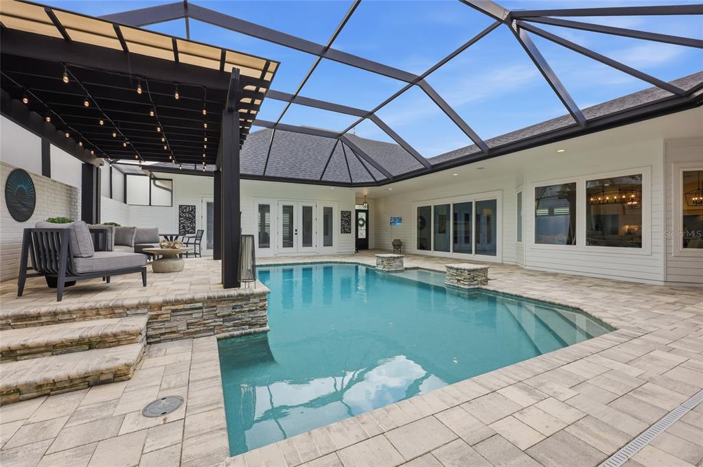 A screened-in patio features a swimming pool, stone accents, and a covered seating area — 1045 SW 132 STREET, NEWBERRY, FL