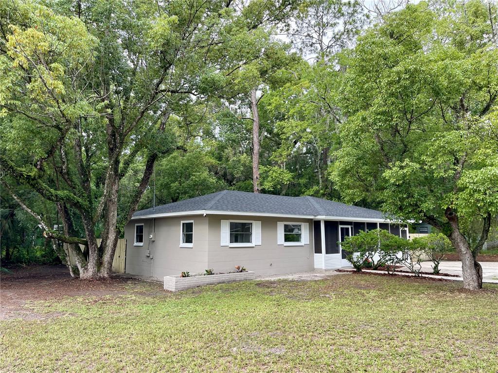 A single-story house with a gray exterior, white trim, and a screened porch — 1715 NE 6TH PLACE, GAINESVILLE, FL