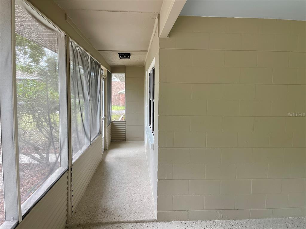 A screened-in porch features a concrete floor, beige block walls, and a ceiling light fixture — 1715 NE 6TH PLACE, GAINESVILLE, FL