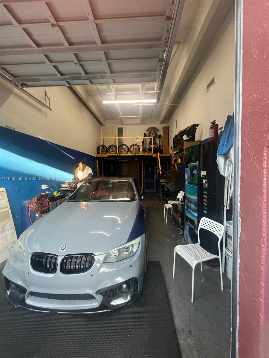 A gray BMW is parked inside a garage with a loft storage area — 3056 S State Road 7 # 1P, Miramar FL 33023, MIRAMAR, FL