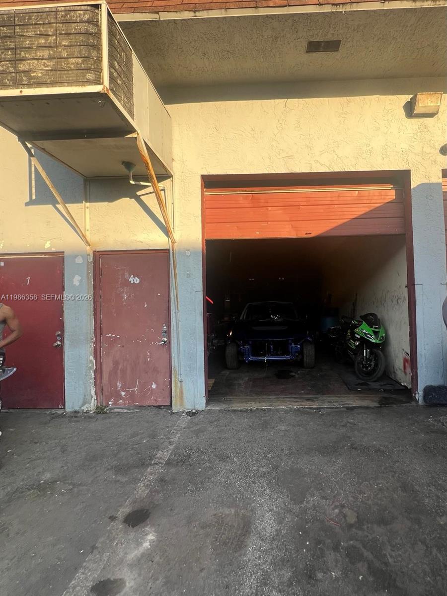 An exterior view of a commercial bay with two red doors and an open garage — 3056 S State Road 7 # 1P, Miramar FL 33023, MIRAMAR, FL