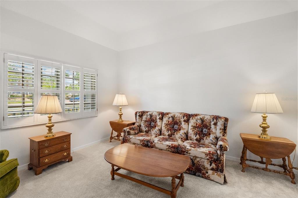 A living room features a floral sofa, wooden end tables, lamps, and white plantation shutters — 1610 BEULAH ROAD, WINTER GARDEN, FL