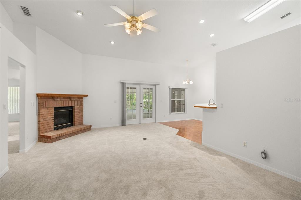 A living room features a brick fireplace, beige carpeting, a ceiling fan, and glass doors — 1610 BEULAH ROAD, WINTER GARDEN, FL