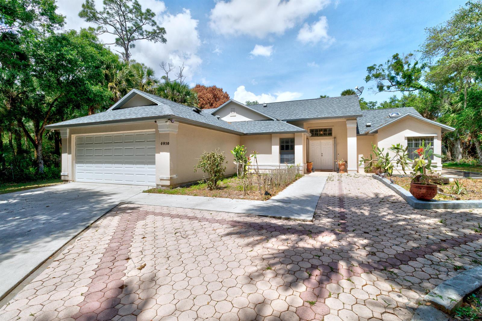 A single-story house with a two-car garage and a paved driveway surrounded by trees — 6930 41st Street, Vero Beach FL 32967, VERO BEACH, FL