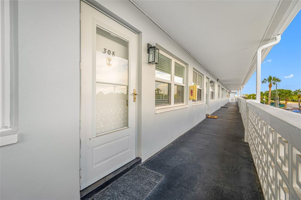 An exterior walkway leads to the entrance of unit 308 with a white door — 1001 77TH AVENUE N UNIT 308, ST PETERSBURG, FL