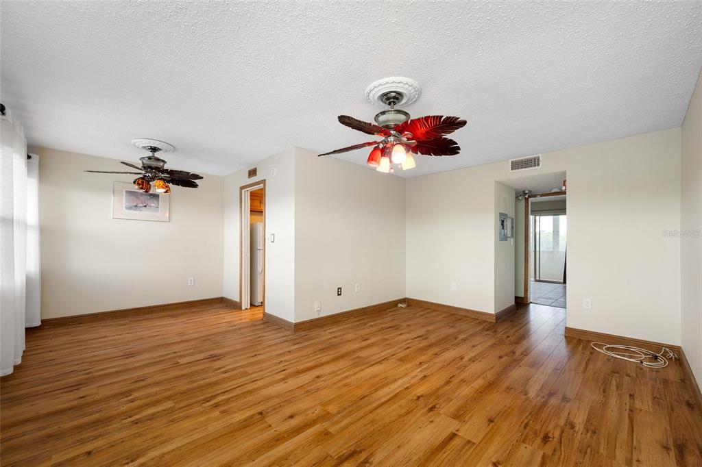 An empty living room features wood-look flooring, two ceiling fans, and light-colored walls — 1001 77TH AVENUE N UNIT 308, ST PETERSBURG, FL