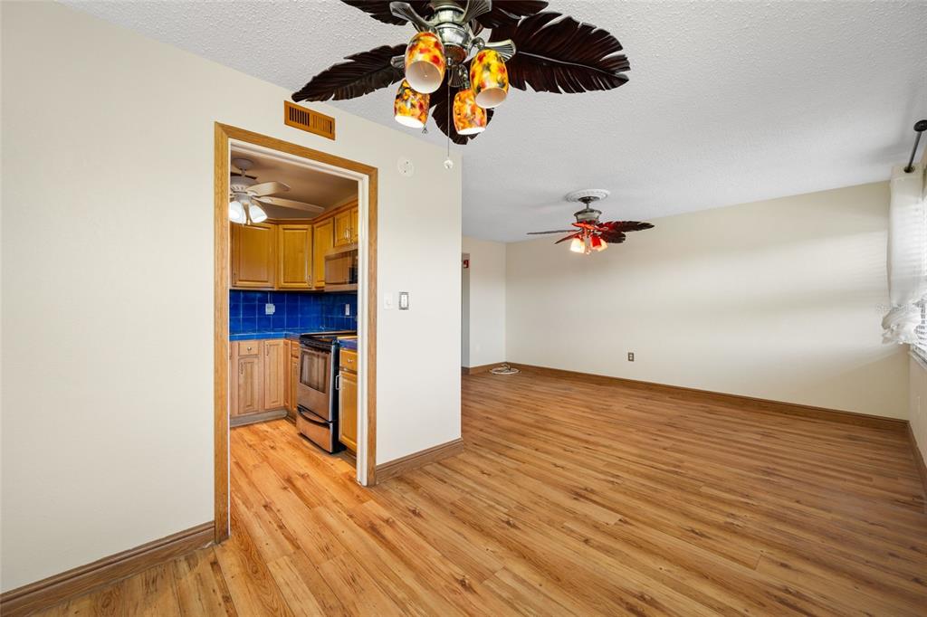 A view of a living room with wood-look flooring and two tropical-style ceiling fans — 1001 77TH AVENUE N UNIT 308, ST PETERSBURG, FL