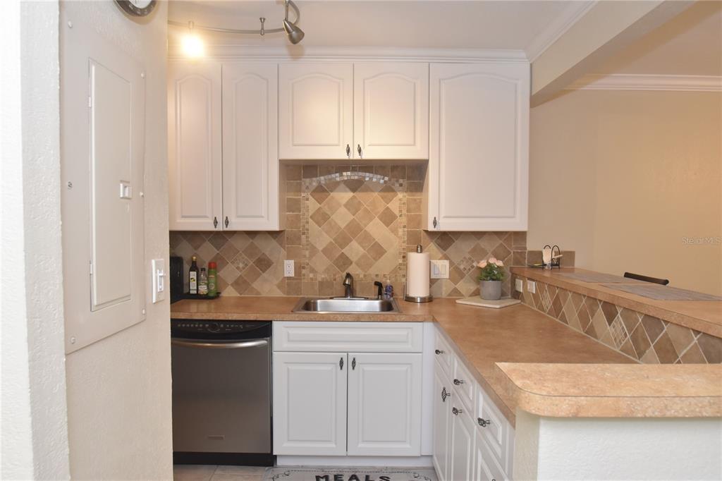 A kitchen features white cabinets, a stainless steel dishwasher, and a tiled backsplash — 3700 S OSPREY AVENUE UNIT 315, SARASOTA, FL