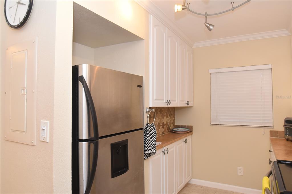 A kitchen features white cabinets, stainless steel appliances, a tan countertop, and a tiled backsplash — 3700 S OSPREY AVENUE UNIT 315, SARASOTA, FL