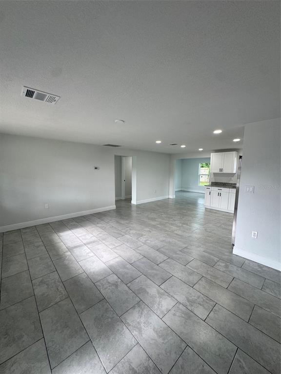 An open-concept living area features gray tile flooring, recessed lighting, and a white kitchen — 6840 RUNNEL DRIVE, NEW PORT RICHEY, FL