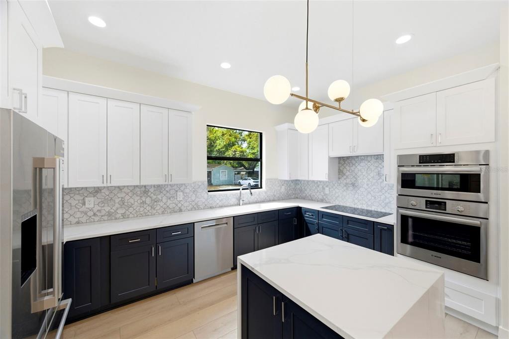 A kitchen features white upper cabinets, dark lower cabinets, a central island, and stainless appliances — 4543 26TH AVENUE S, ST PETERSBURG, FL
