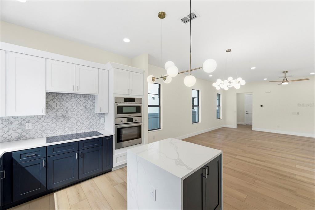 A modern kitchen features white upper cabinets, dark blue lower cabinets, and a marble-topped island — 4543 26TH AVENUE S, ST PETERSBURG, FL