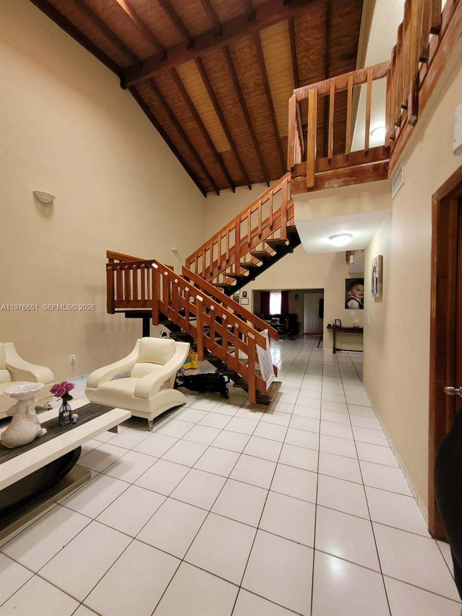 A living room features a high vaulted wood-paneled ceiling, white tile floors, and a wooden staircase — 10932 SW 25th St, Miami FL 33165, MIAMI, FL
