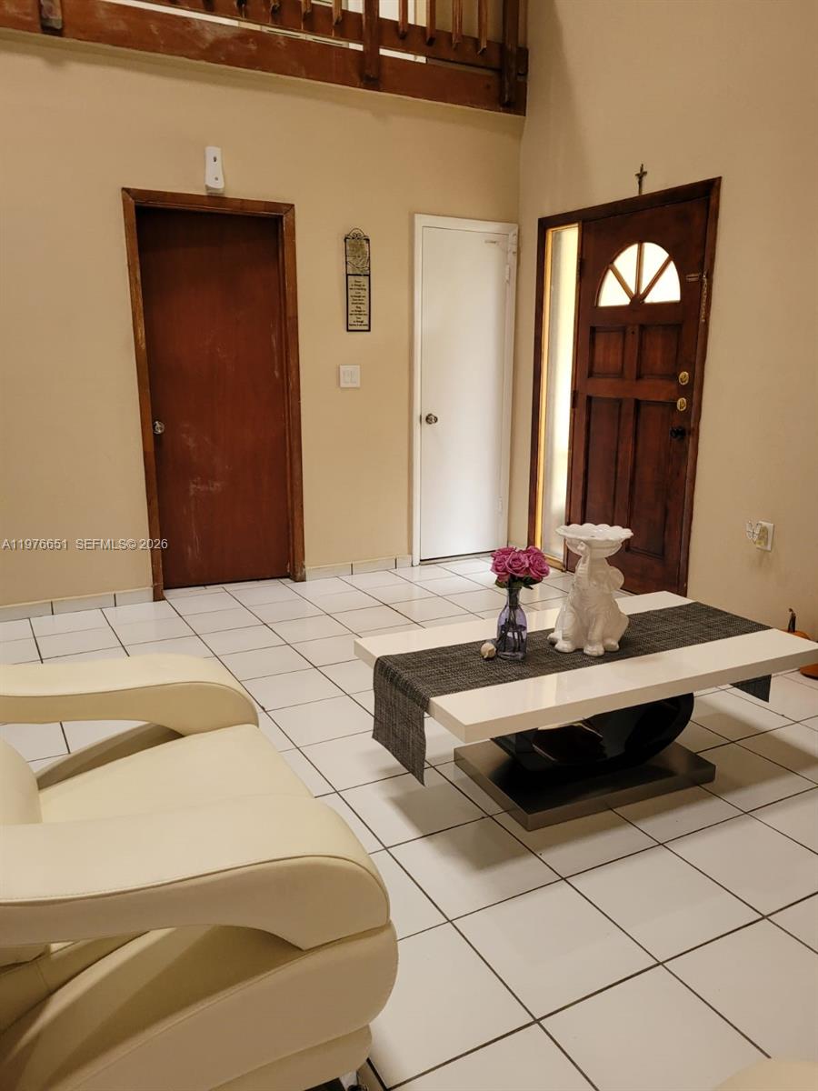 A living room features white tile flooring, a modern coffee table, and two interior doors — 10932 SW 25th St, Miami FL 33165, MIAMI, FL
